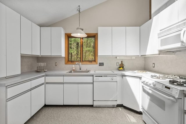 kitchen featuring vaulted ceiling, a sink, light countertops, white cabinets, and white appliances
