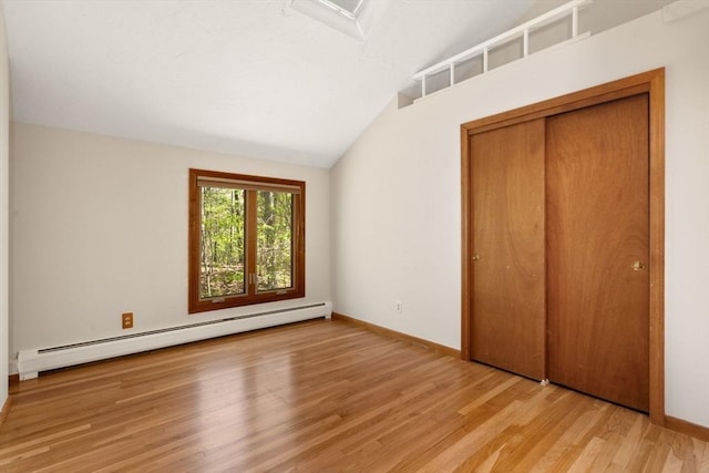 unfurnished bedroom with a closet, wood finished floors, lofted ceiling, baseboards, and baseboard heating