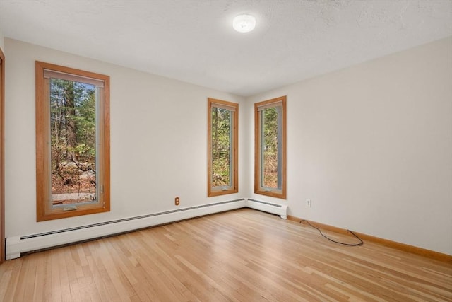 empty room with baseboards, a baseboard radiator, and wood finished floors
