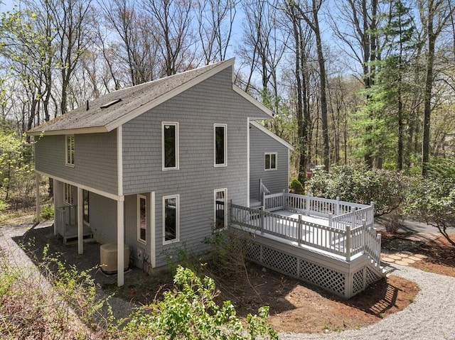 back of property with a wooden deck and central AC