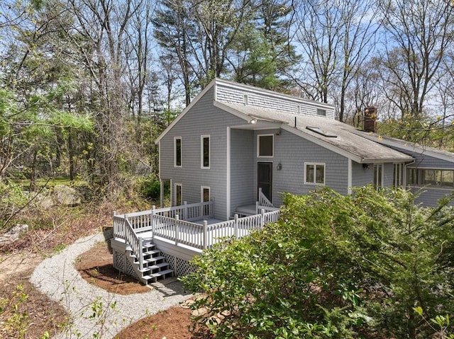 view of front of home with a chimney, roof with shingles, and a deck