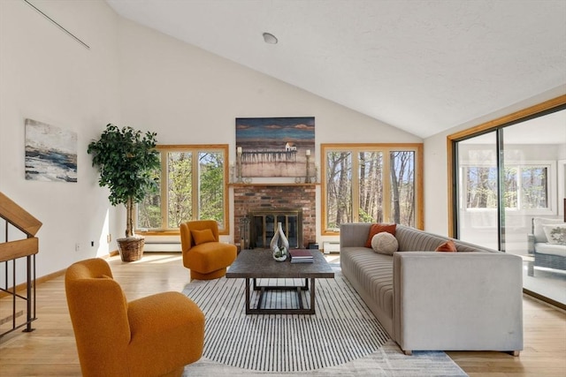 living area featuring a brick fireplace, high vaulted ceiling, plenty of natural light, and wood finished floors