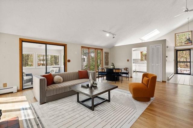 living area featuring light wood finished floors, lofted ceiling with skylight, and a baseboard heating unit