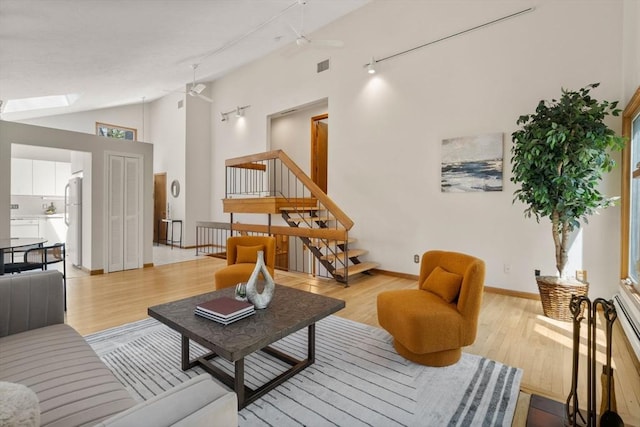 living area featuring a skylight, a ceiling fan, light wood-type flooring, and visible vents