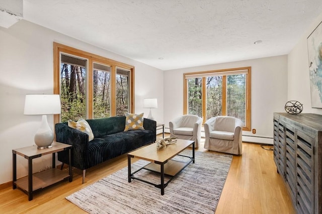 living area with baseboards, a baseboard heating unit, light wood finished floors, and a textured ceiling
