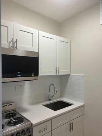1258 Commonwealth Ave Unit 8, Boston, MA 02134 - kitchen with stainless steel appliances, a sink, decorative backsplash, and light countertops