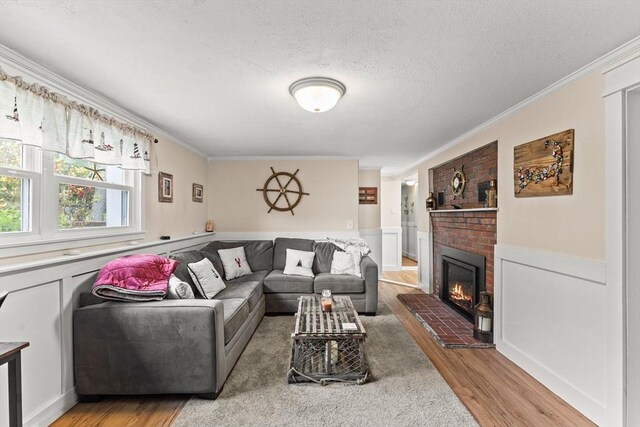 8 Stackpole Cir, Bourne, MA 02532 - living room with light wood-style floors, crown molding, a textured ceiling, a brick fireplace, and a wainscoted wall