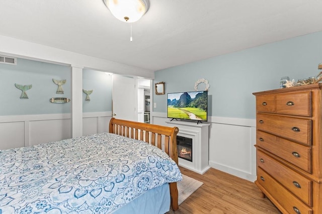 8 Stackpole Cir, Bourne, MA 02532 - bedroom with light wood finished floors, a wainscoted wall, and a glass covered fireplace