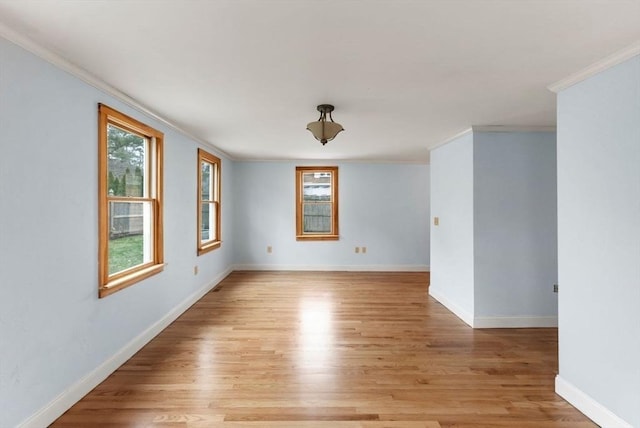 empty room featuring ornamental molding, baseboards, and light wood-type flooring