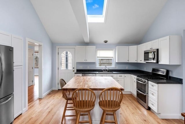 kitchen with white cabinetry, a kitchen bar, a sink, and stainless steel appliances