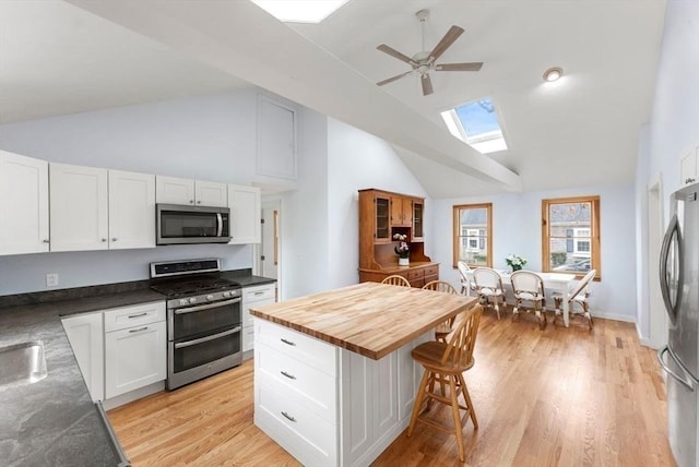 kitchen with a kitchen breakfast bar, white cabinets, stainless steel appliances, and a skylight