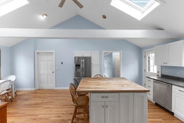 kitchen featuring white cabinetry, a kitchen breakfast bar, appliances with stainless steel finishes, butcher block counters, and ceiling fan