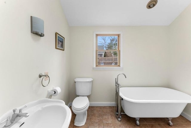 full bathroom featuring baseboards, a sink, a freestanding tub, and tile patterned floors