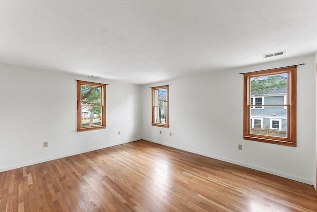 spare room featuring baseboards, visible vents, and wood finished floors