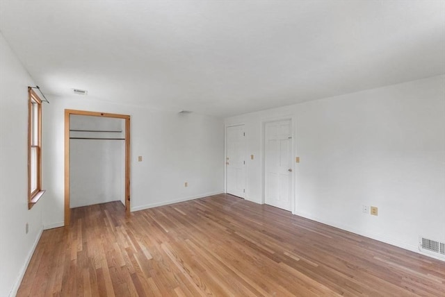 unfurnished bedroom with baseboards, light wood finished floors, and visible vents