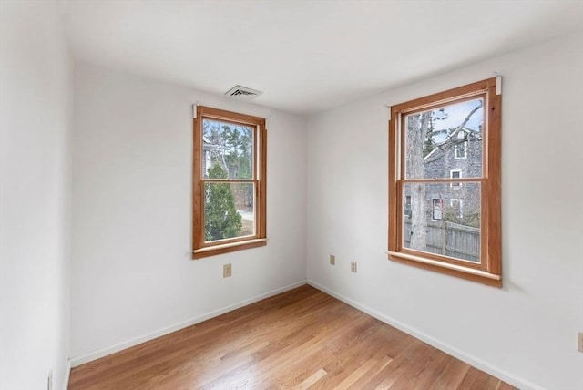 spare room featuring visible vents, baseboards, and light wood-type flooring