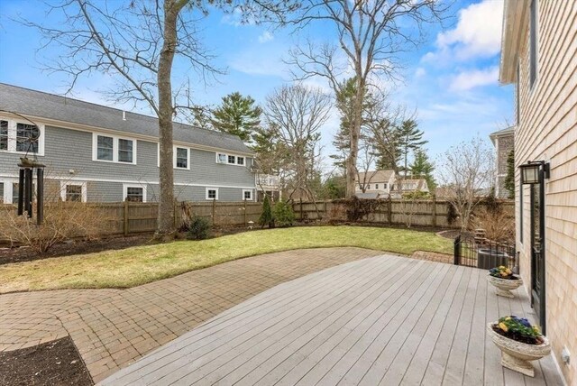 wooden deck featuring a lawn, a fenced backyard, and a patio area