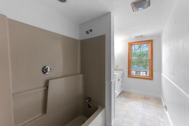 full bath with a textured ceiling, tile patterned floors, vanity, wainscoting, and shower / bathtub combination