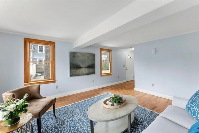 living area with beam ceiling, baseboards, and light wood-type flooring