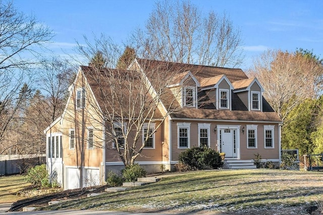 new england style home featuring a shingled roof, a front yard, and fence