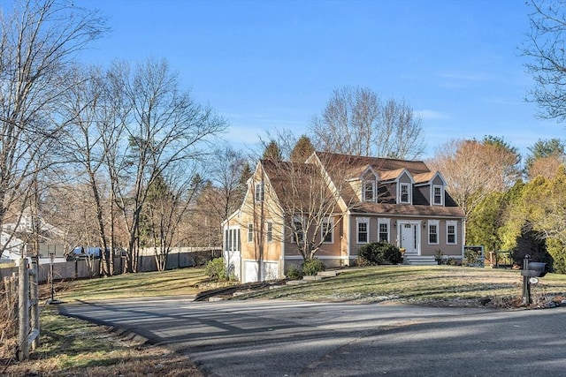 cape cod house with fence and a front lawn