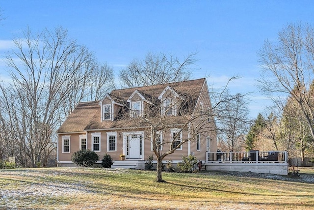 cape cod home featuring a front yard and a wooden deck