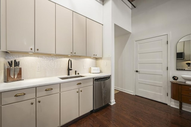 kitchen with sink, tasteful backsplash, white cabinets, dark hardwood / wood-style flooring, and stainless steel dishwasher