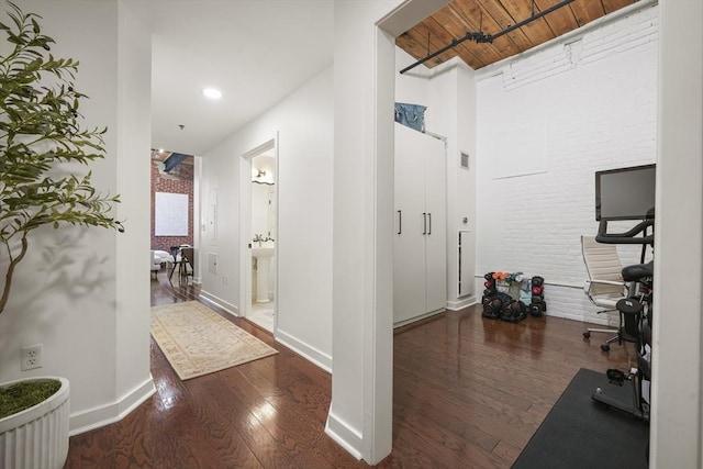 interior space featuring dark hardwood / wood-style flooring, wooden ceiling, and brick wall