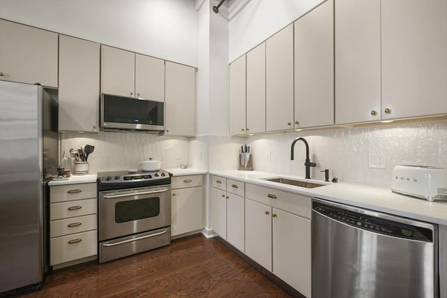 kitchen with stainless steel appliances, tasteful backsplash, sink, and white cabinetry