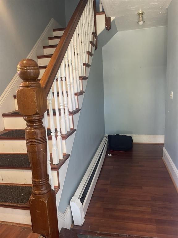 stairway featuring hardwood / wood-style floors and a baseboard radiator