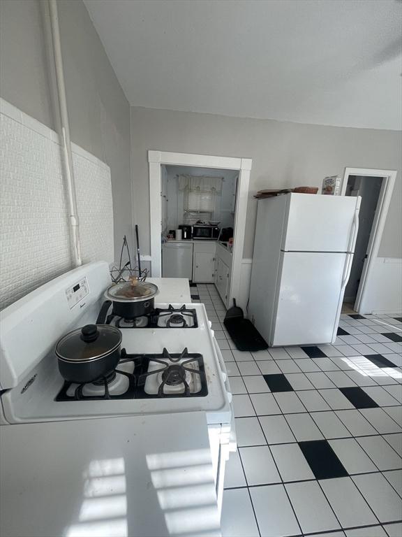 kitchen featuring white cabinets, light tile patterned flooring, and white appliances