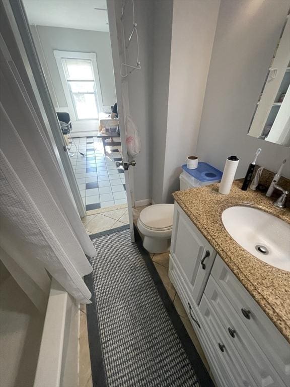 bathroom with toilet, vanity, and tile patterned floors