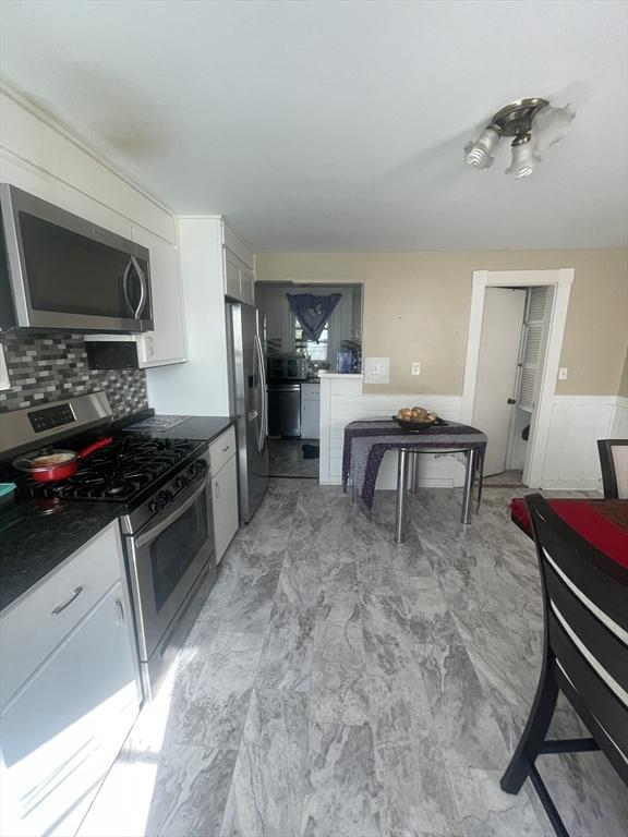 kitchen featuring decorative backsplash, appliances with stainless steel finishes, and white cabinetry