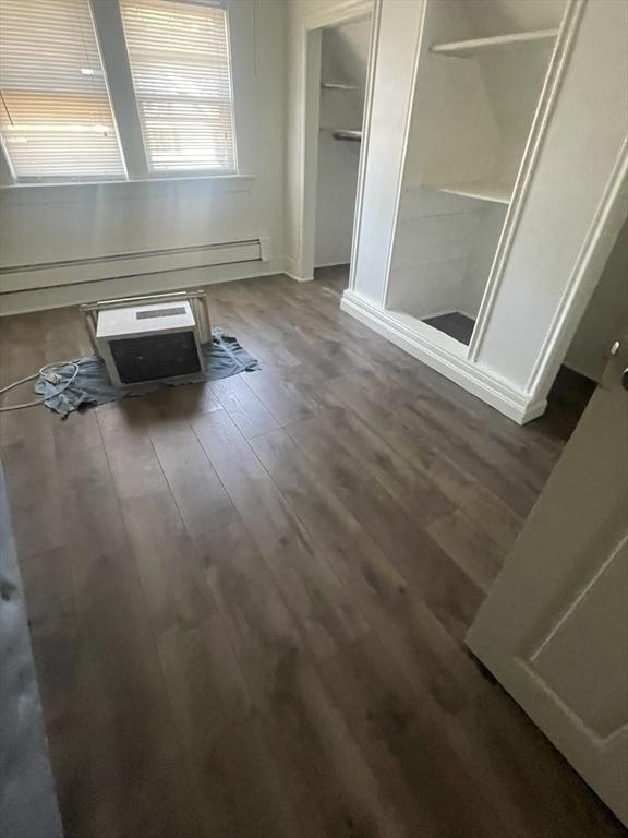 unfurnished bedroom with a baseboard radiator and dark hardwood / wood-style floors