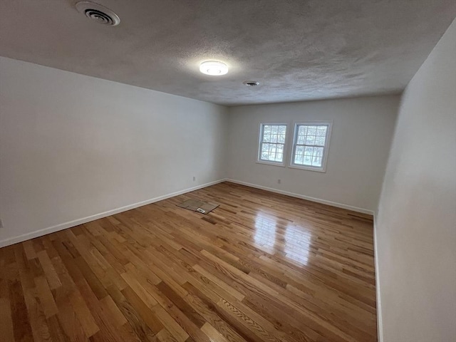 unfurnished room with light hardwood / wood-style floors and a textured ceiling