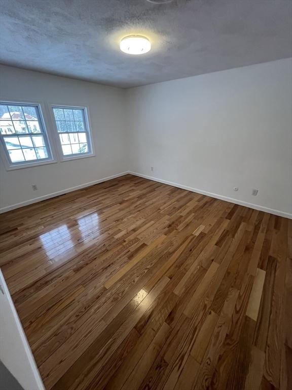 empty room with hardwood / wood-style flooring and a textured ceiling