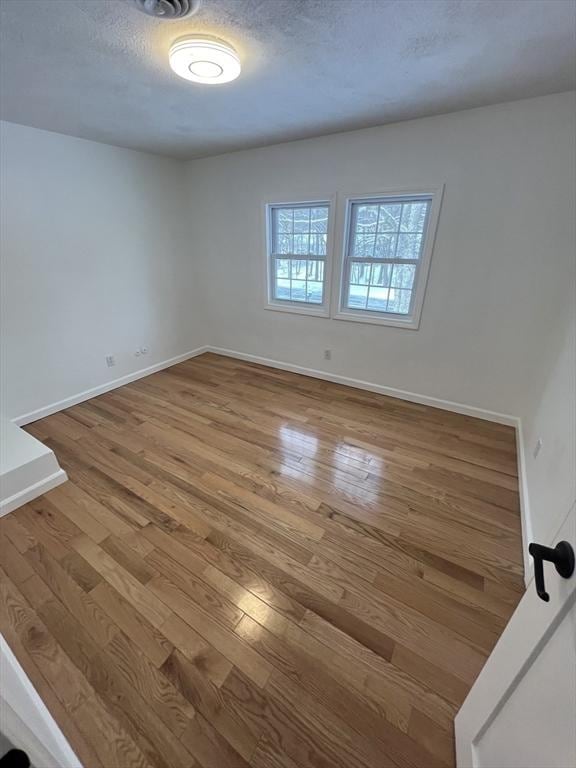 spare room featuring hardwood / wood-style floors and a textured ceiling