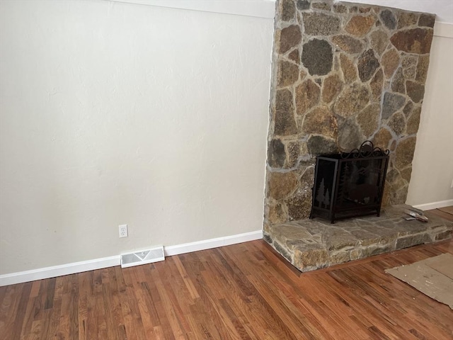 room details featuring wood-type flooring and a stone fireplace