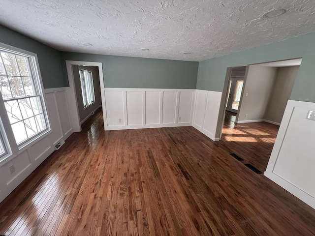 unfurnished room featuring a textured ceiling and dark hardwood / wood-style flooring