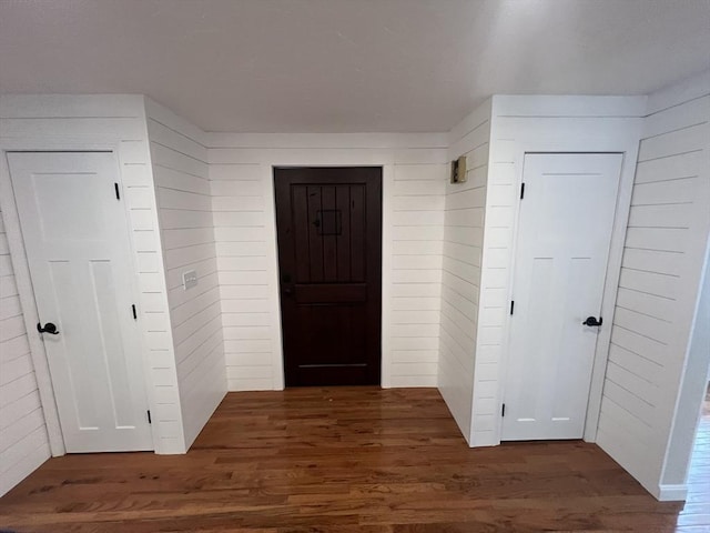 interior space featuring dark wood-type flooring and wooden walls