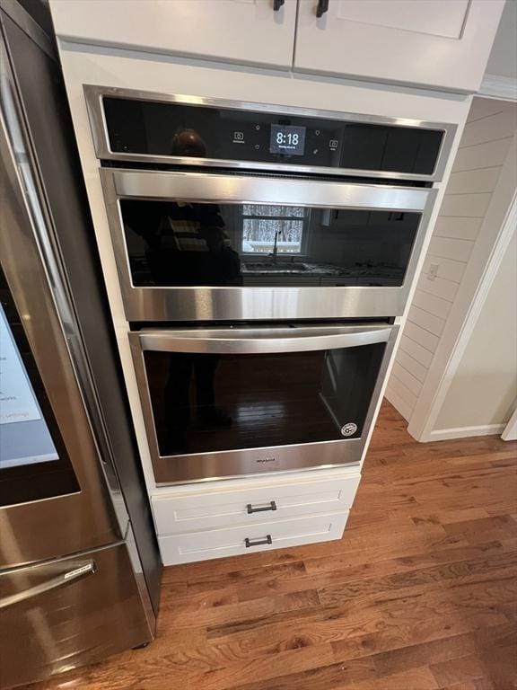 interior details featuring white cabinetry, double oven, and wood-type flooring