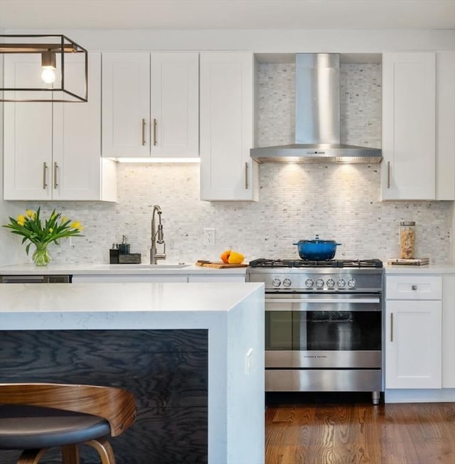 kitchen with tasteful backsplash, gas range, wall chimney range hood, and white cabinets