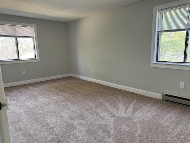 carpeted empty room with a healthy amount of sunlight, a textured ceiling, and baseboards