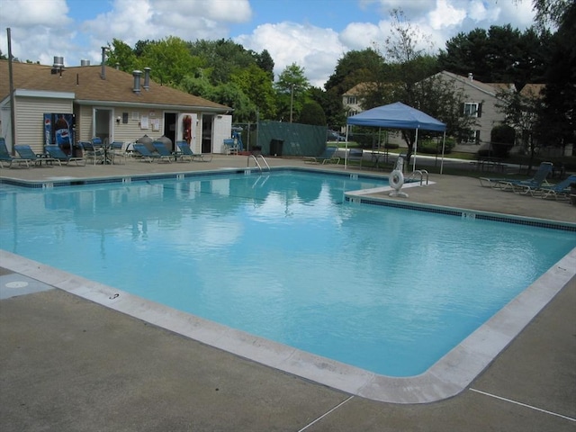 pool with a patio area and fence