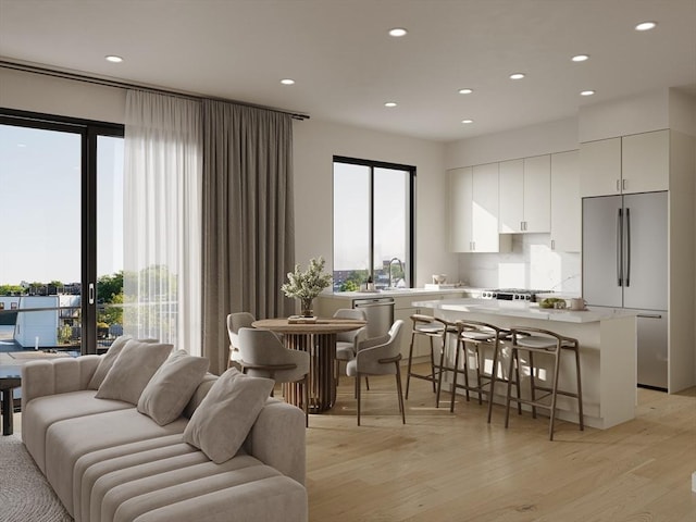 interior space featuring white cabinetry, stainless steel appliances, light wood-type flooring, a breakfast bar, and a center island