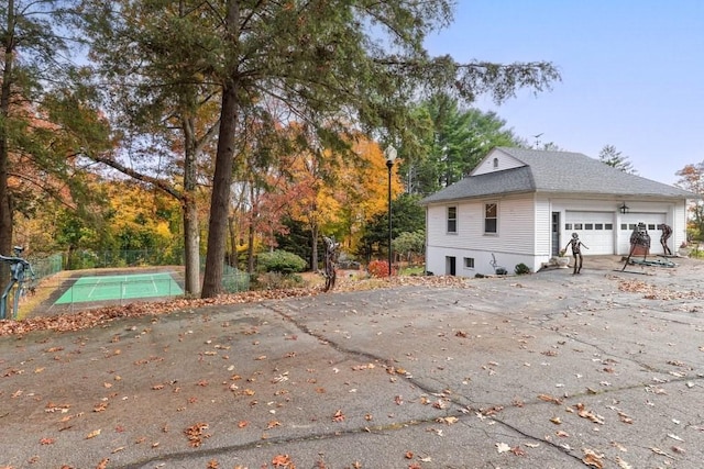 view of side of property with tennis court and a garage