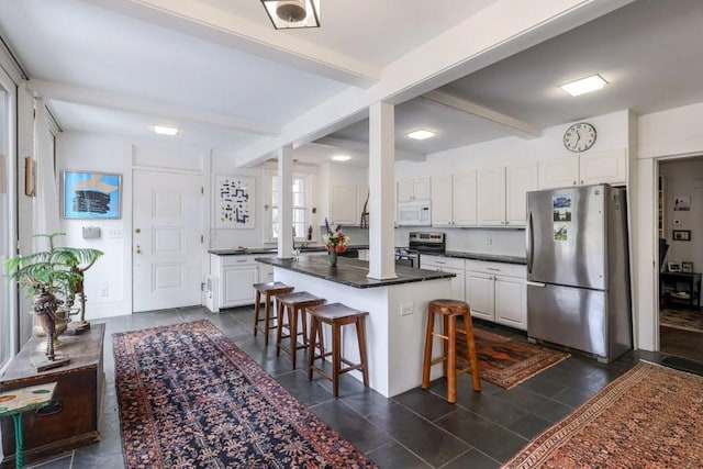 kitchen featuring a breakfast bar, beam ceiling, white cabinetry, and stainless steel appliances