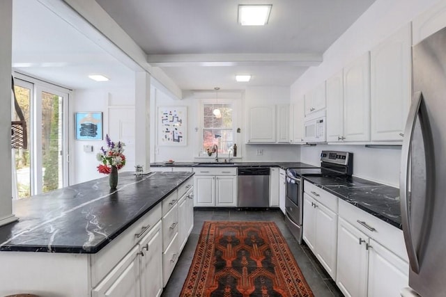 kitchen featuring sink, stainless steel appliances, beamed ceiling, dark stone counters, and white cabinets