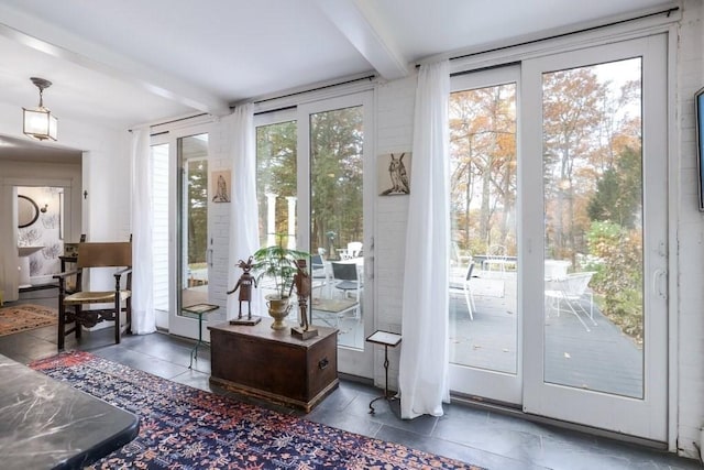 doorway to outside featuring beam ceiling and dark tile patterned flooring