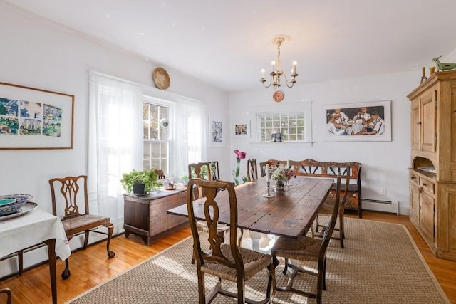 dining area featuring an inviting chandelier, light hardwood / wood-style flooring, and a baseboard heating unit